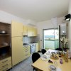 Cucina moderna con mobili gialli, tavolo apparecchiato e vista mare dalla finestra.