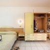 Camera da letto con letto matrimoniale, armadio aperto, portatile sul letto e vestiti appesi.