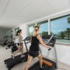 Due persone su tapis roulant in una palestra luminosa con finestre.