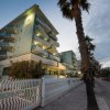 Un edificio residenziale moderno con balconi e palme lungo la strada al tramonto.