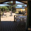 Vista dalla veranda verso altri chalet, con tavolo e sedie bianche.