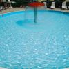 Piscina rotonda con una fontana centrale e sedie a sdraio tutt'intorno.