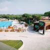 Piscina olimpionica all'aperto, bar e biciclette parcheggiate, circondata da verde.