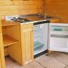 Mini cucina in legno con frigorifero aperto, lavello e fornelli.
