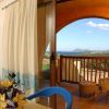Sala con tavolo e fiori, porta su balcone con vista mare, divano blu visibile.