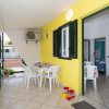 Veranda gialla con tavolo rotondo e sedie bianche, affaccio su un giardino.