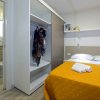 Camera con letto matrimoniale, coperta arancione, asciugamani, armadio aperto e bagno a vista.