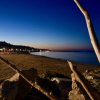 Spiaggia al tramonto con cielo blu scuro e luci accese sul lungomare.