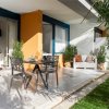 Patio esterno con mobili eleganti e piante in vaso.
