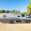 Camper parcheggiato su terreno sabbioso vicino a pini.