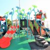 Un parco giochi colorato con scivoli rossi e blu su un pavimento verde.