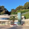 Edificio moderno con palme e vegetazione su una collina.