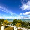 Vista sul mare con cielo blu e alberi in primo piano.