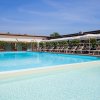 Piscina esterna con lettini e ombrelloni sotto un cielo blu.