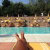Persona su sdraio bordo piscina con ombrelloni gialli.