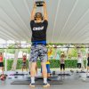 Lezione di fitness all'aperto con istruttore e partecipanti sotto un tendone.
