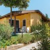 Bungalow giallo con veranda in un giardino fiorito.