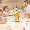 Famiglia seduta intorno a un tavolo al ristorante, sorridendo davanti a un piatto di pizza.
